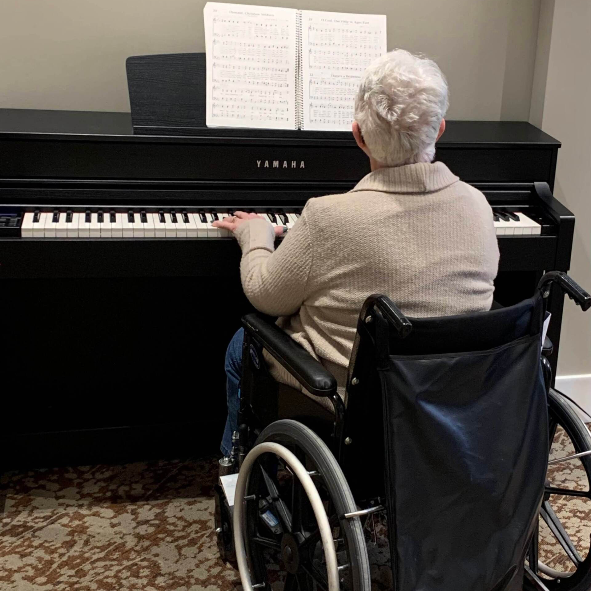 elderly resident reading music notes and playing the piano