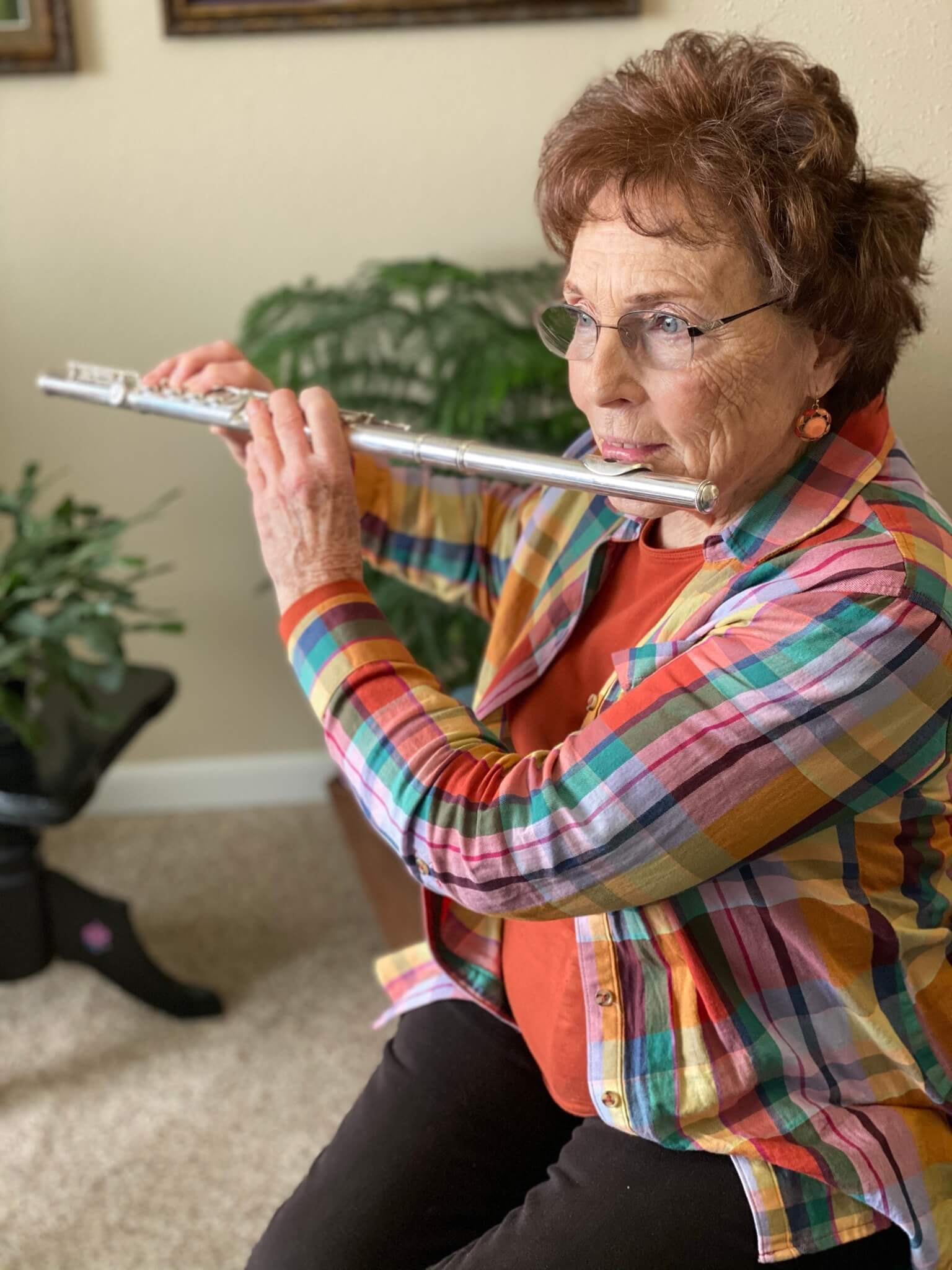 senior woman playing the flute in her senior living apartment