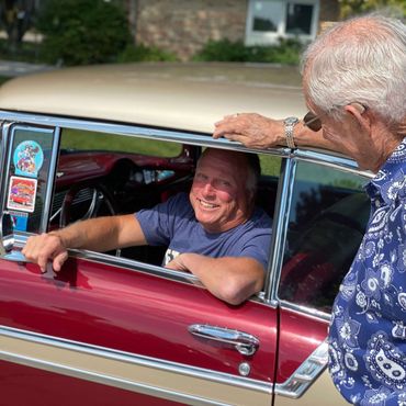 man leaning up against antique car talking to gentleman at retirement community retirement community hobby