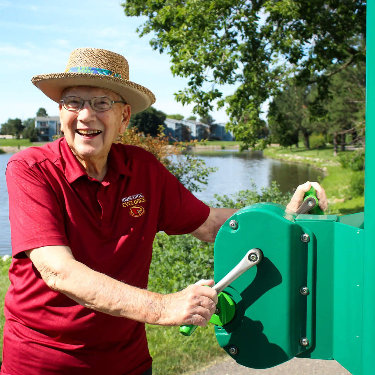 Senior living independent resident exercising outdoors on a green machine by the lake
