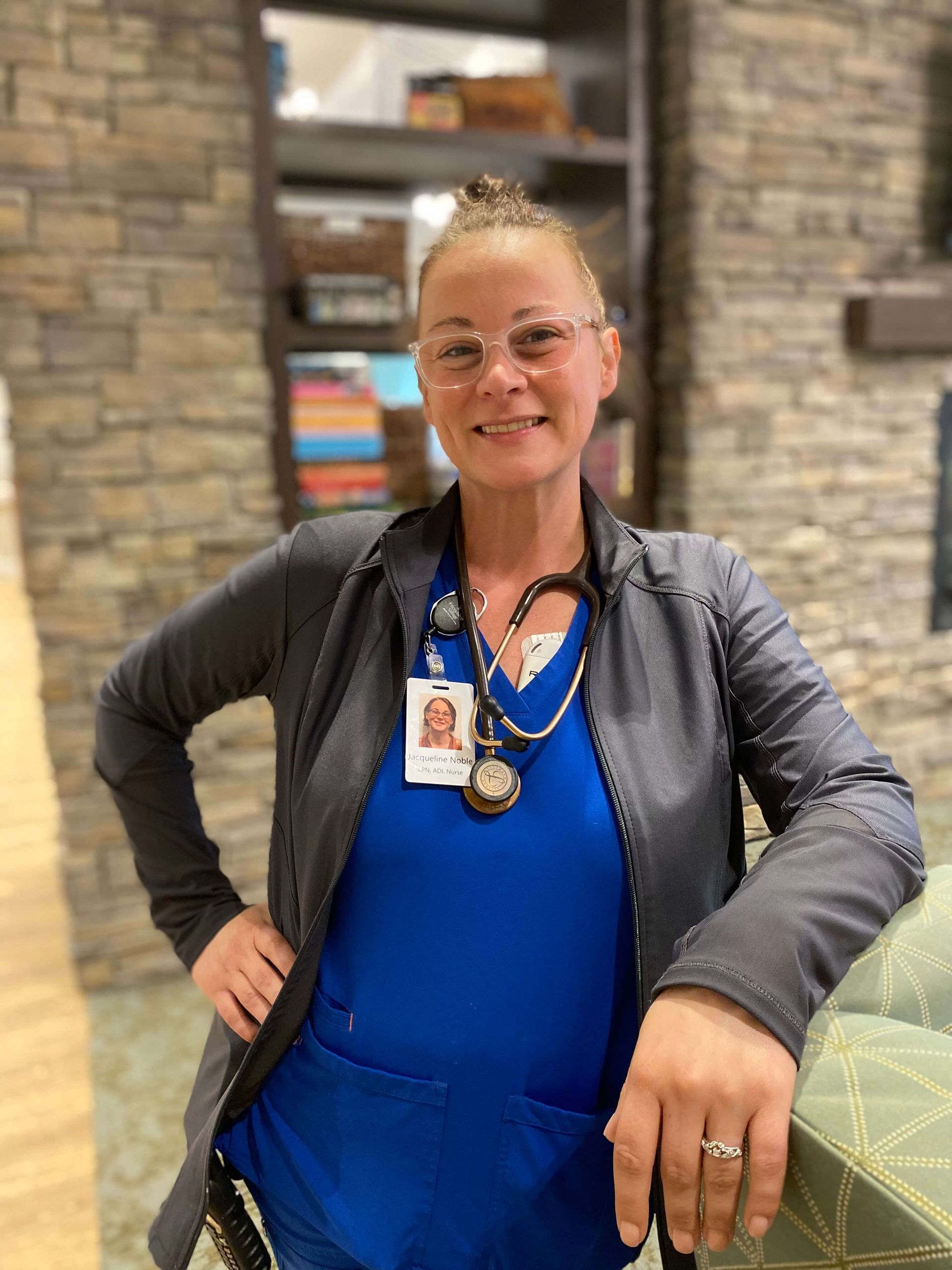 nurse leaning on a chair in front of a bookcase 