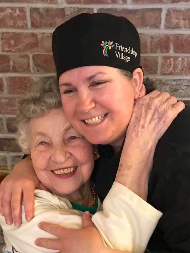 dining team cook hugging elderly resident