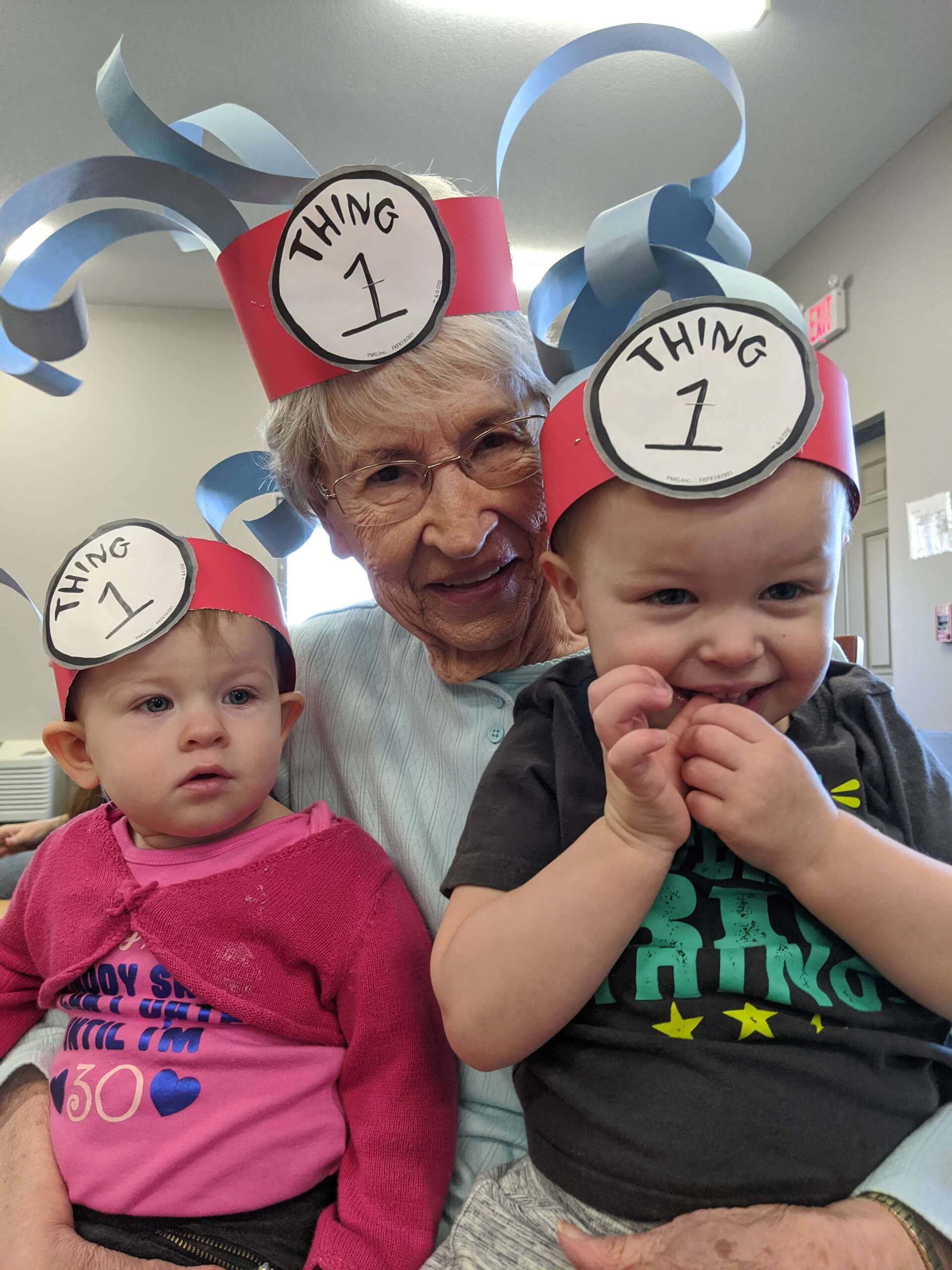 lady holding two kids in her lap with goofy hats on