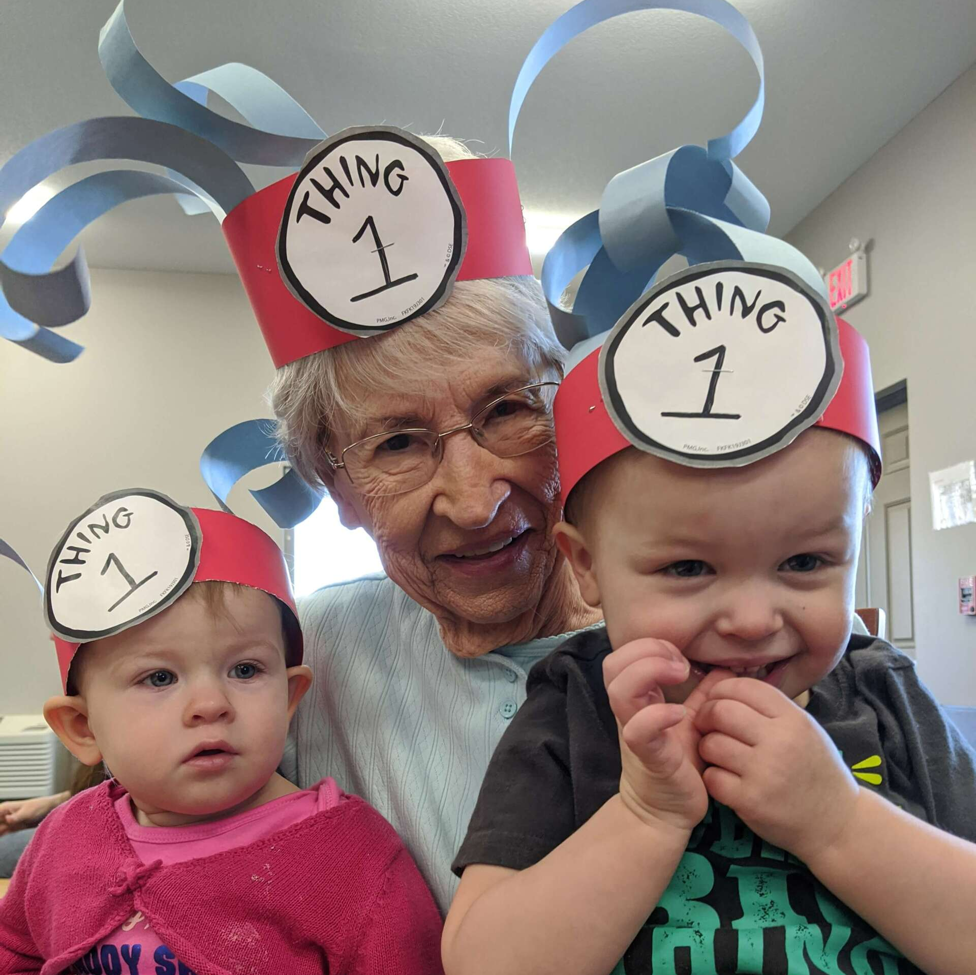lady holding two kids in her lap with goofy hats on