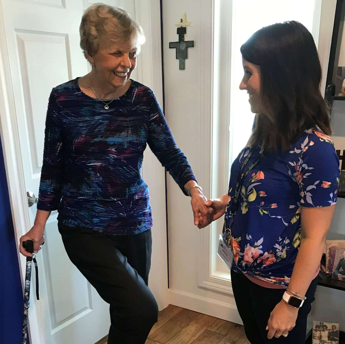 Therapist helping woman balance on one leg while using a cane to stay steady