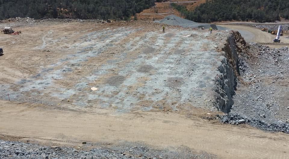 Graded construction site with compacted dirt, gravel, and a stone retaining wall