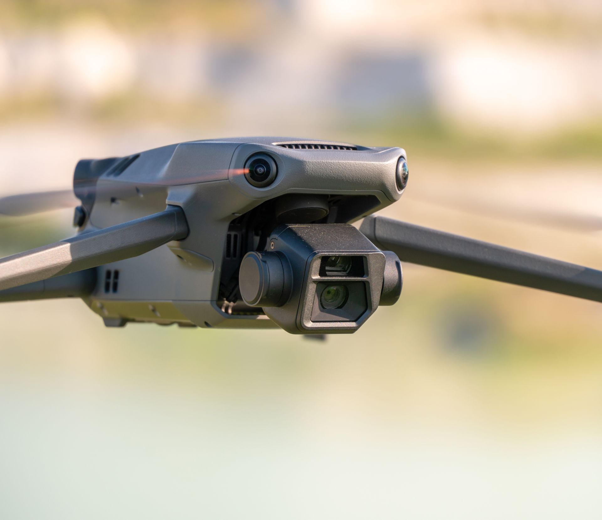 Gray drone with camera hovering outdoors against a blurred background