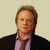 A man in a suit and tie is looking at the camera.