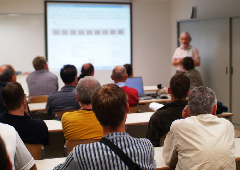 A group of people are sitting in a classroom watching a presentation