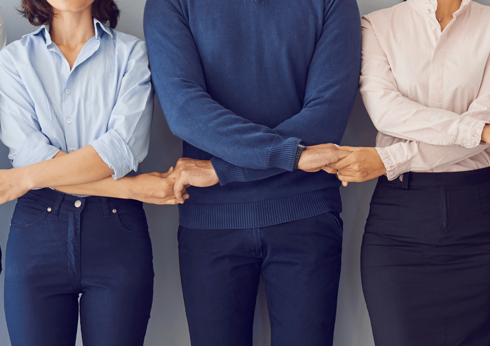 Three people are standing next to each other with their arms crossed.
