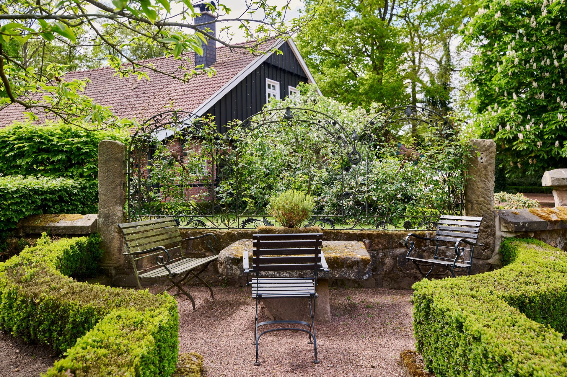 Ein Tisch und Stühle in einem Garten mit einem Haus im Hintergrund.