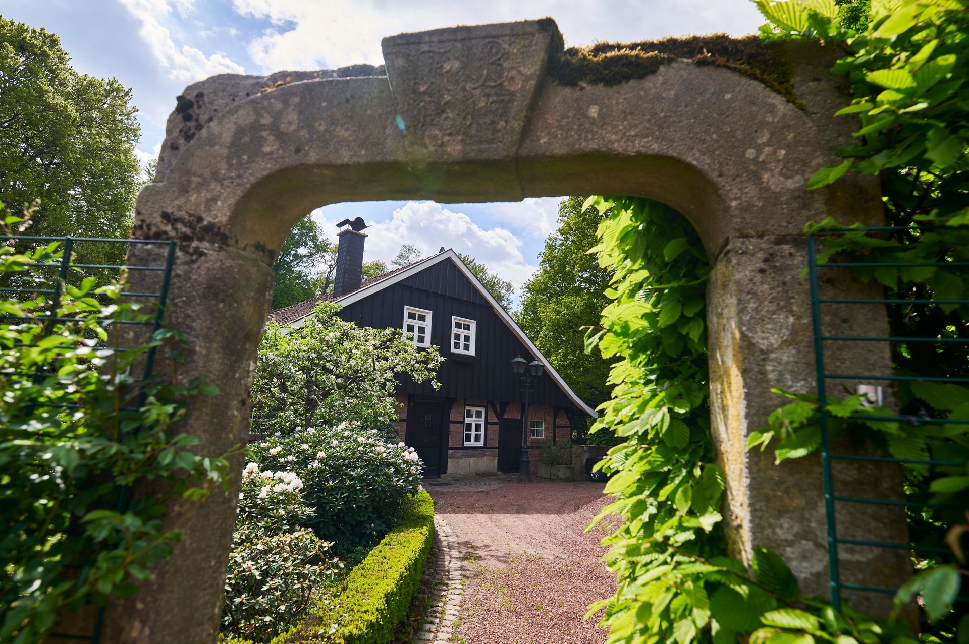 Ein steinerner Torbogen mit einem Haus im Hintergrund