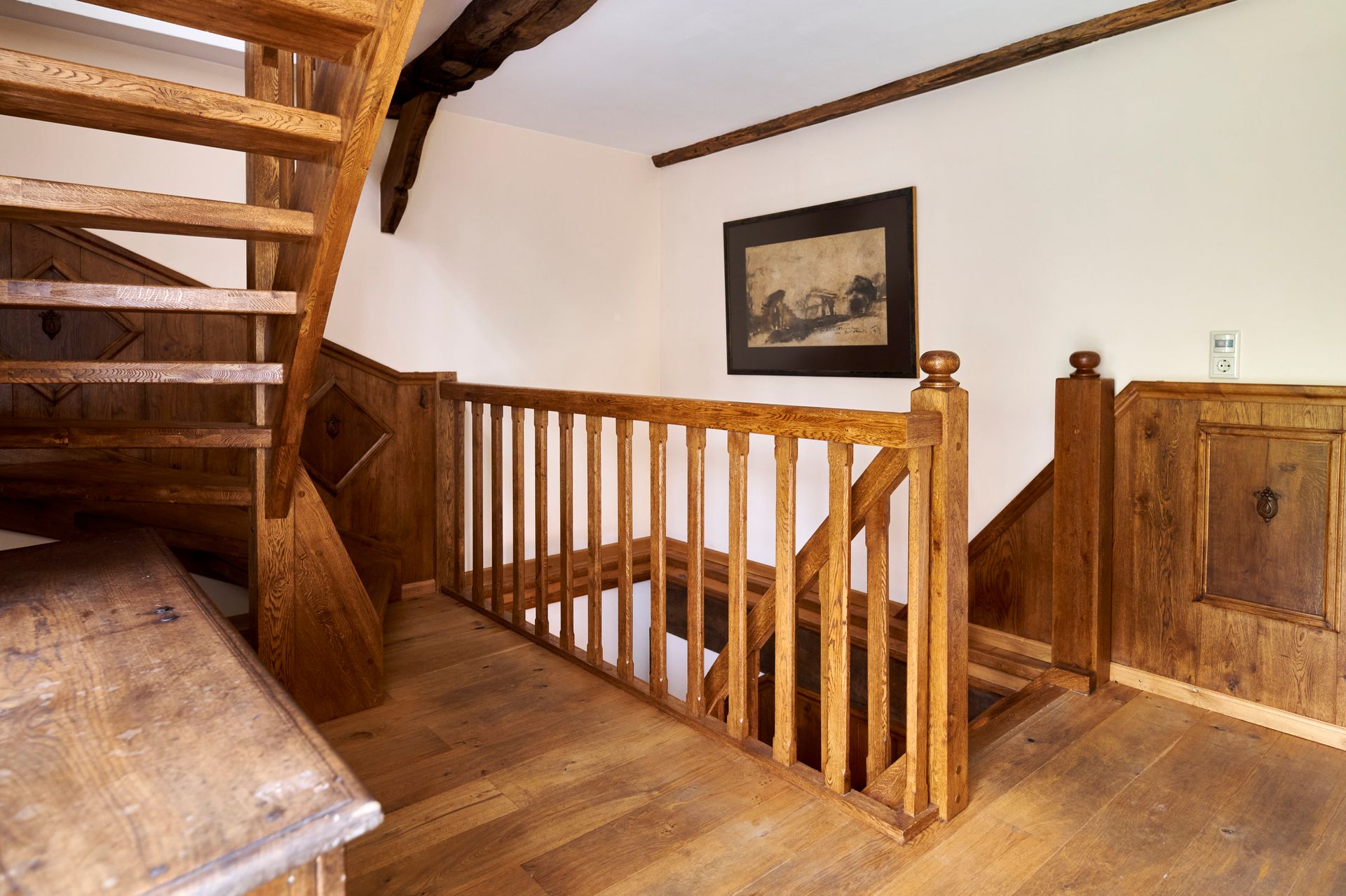 Eine Holztreppe mit Holzgeländer und einem Bild an der Wand.