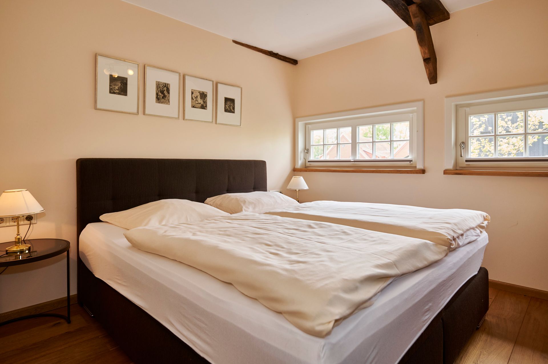 Ein Schlafzimmer mit einem Bett, zwei Lampen und drei Bildern an der Wand.