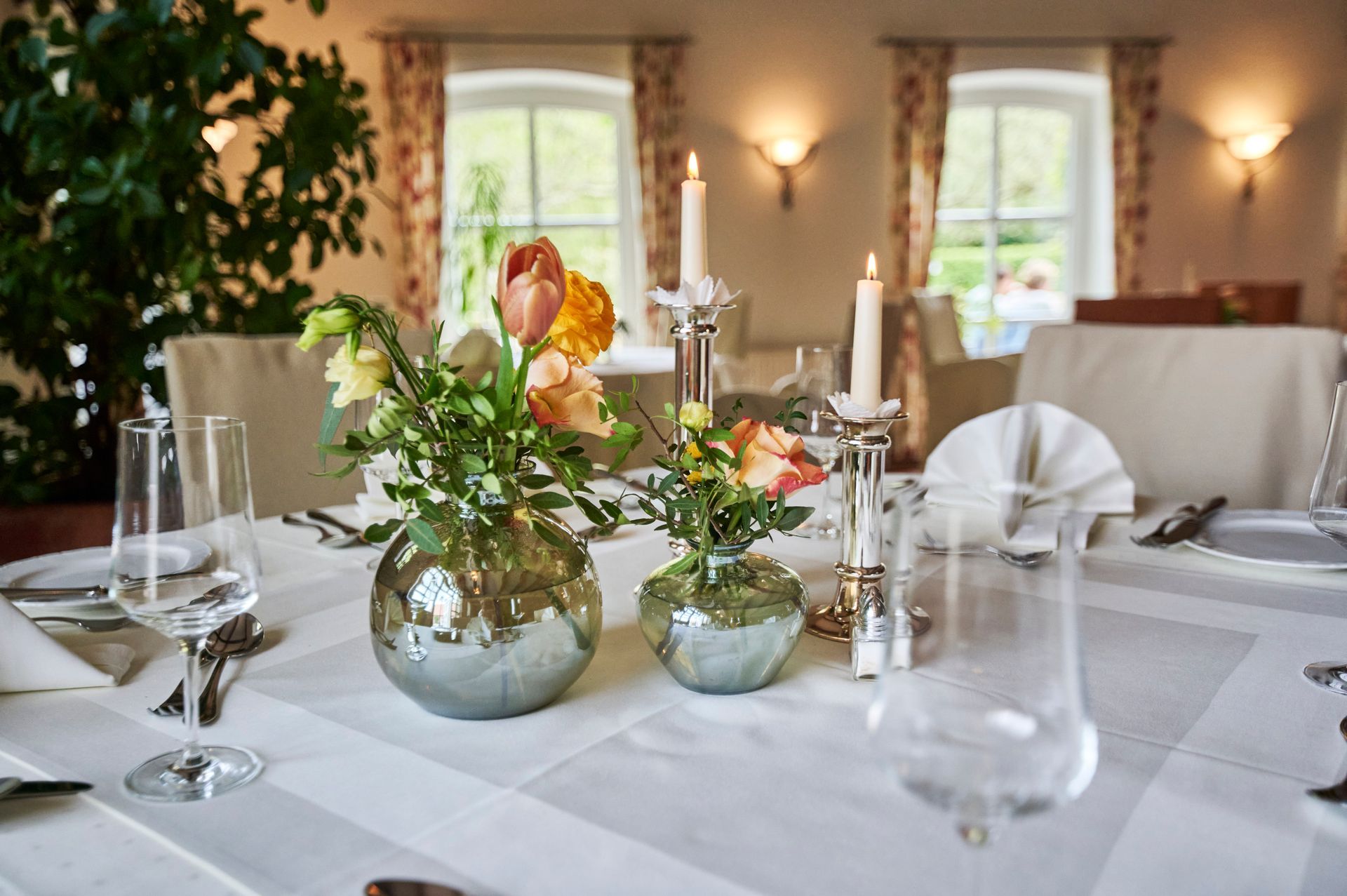 Ein Tisch mit einer Vase mit Blumen und Kerzen darauf.