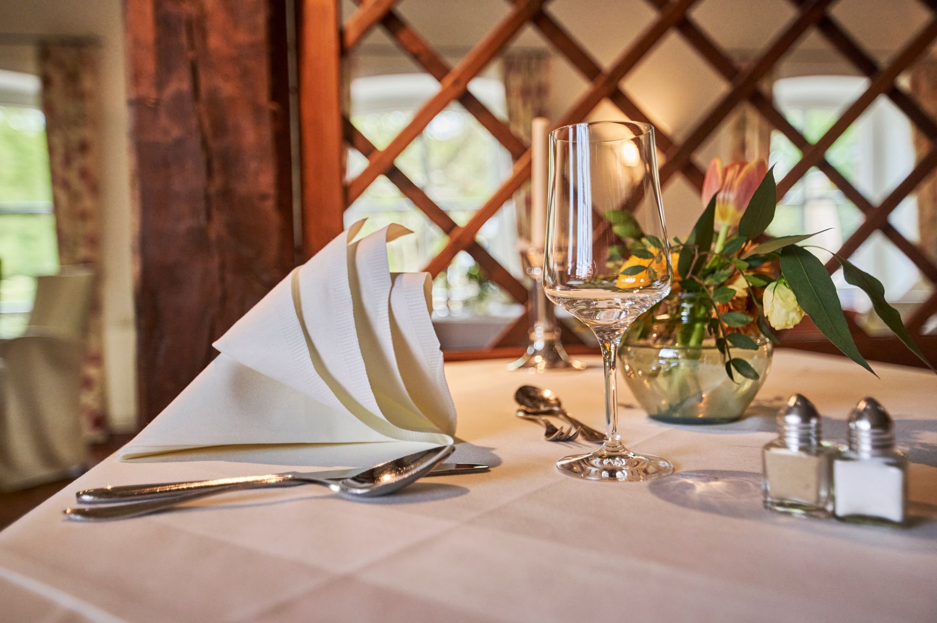 Ein für eine Mahlzeit gedeckter Tisch mit einer Vase Blumen und einem Glas Wein.