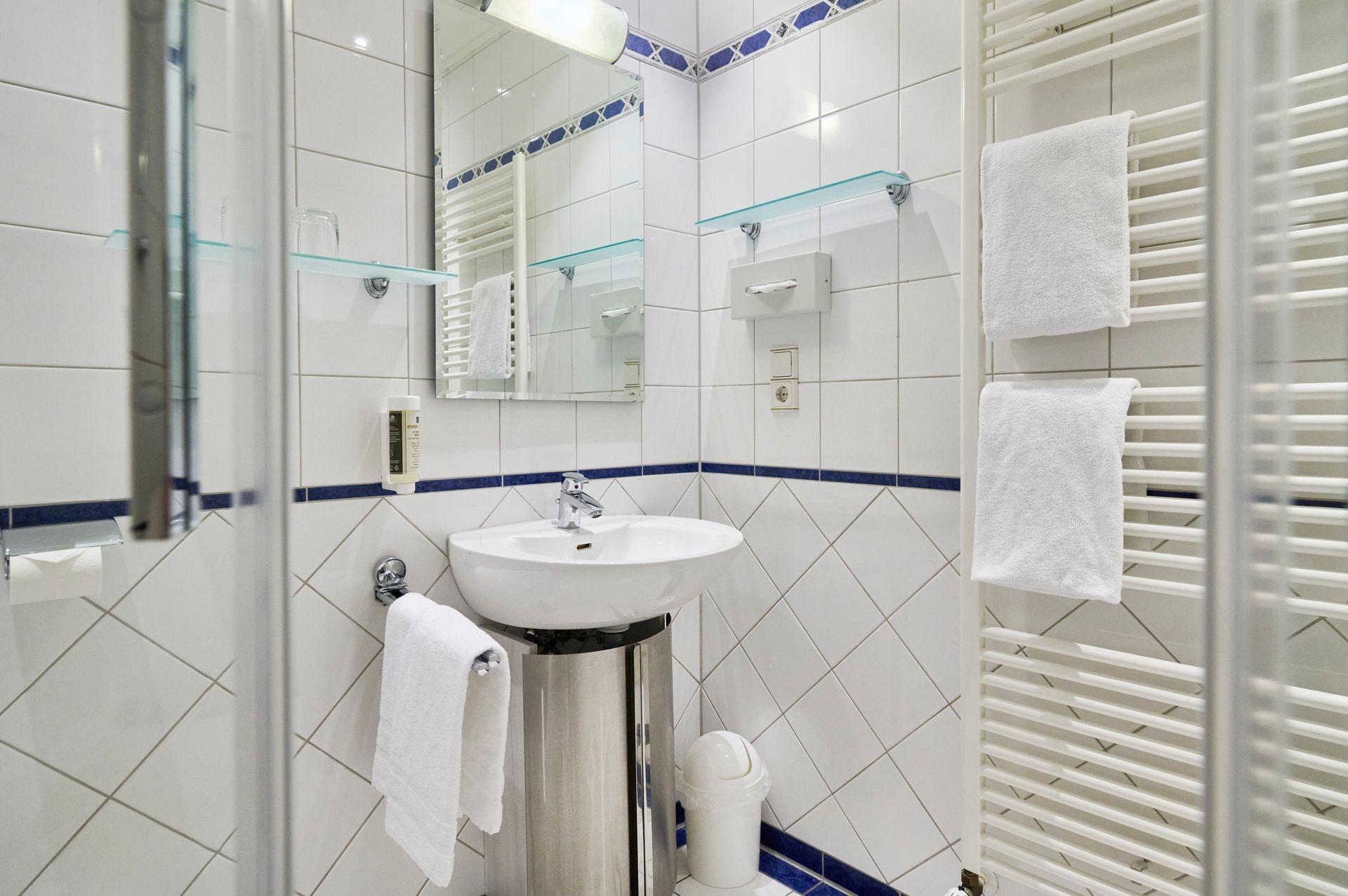 Ein Badezimmer mit Waschbecken, Spiegel und Handtuchhalter