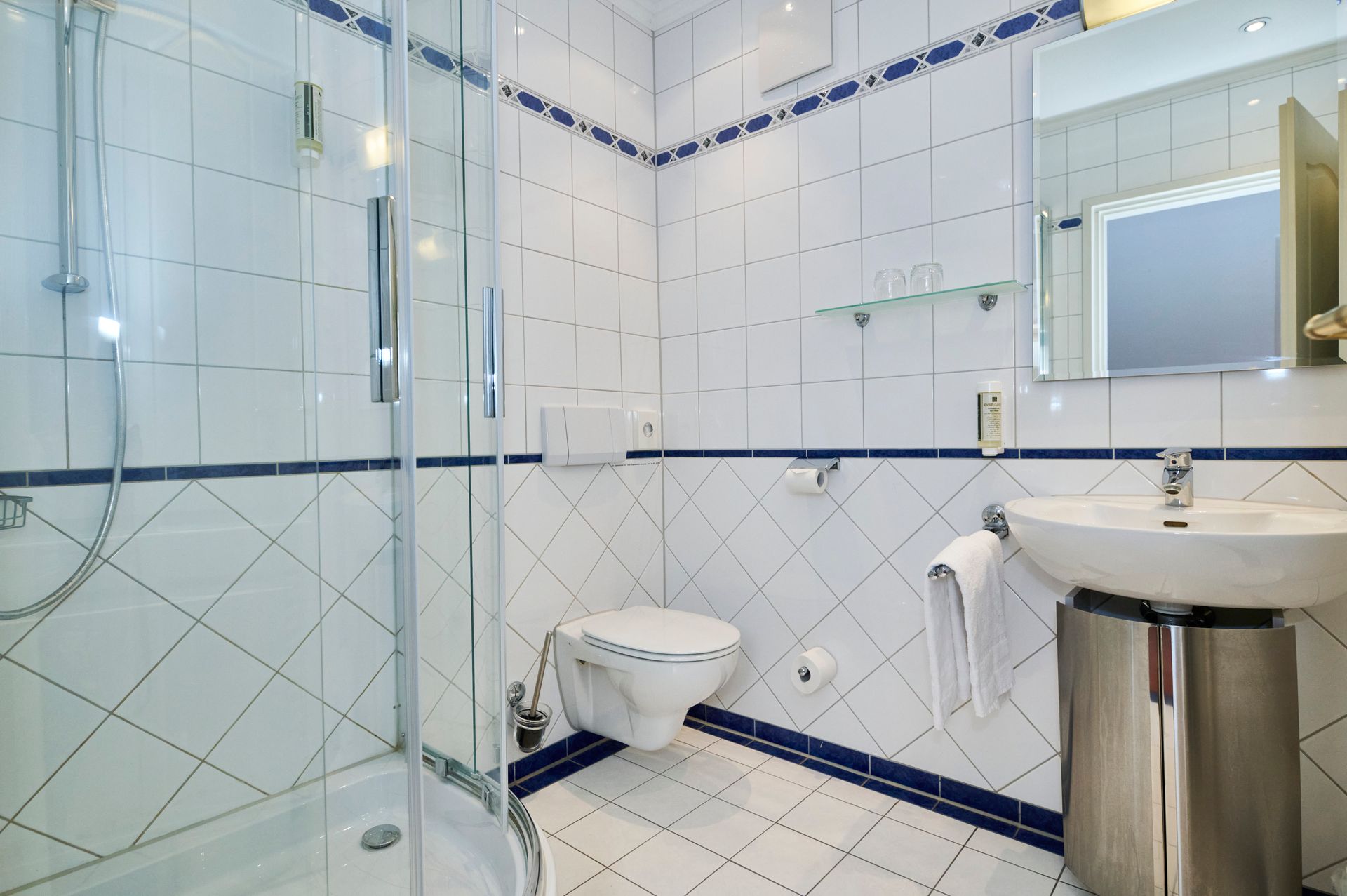 Ein Badezimmer mit Toilette, Waschbecken, Dusche und Spiegel