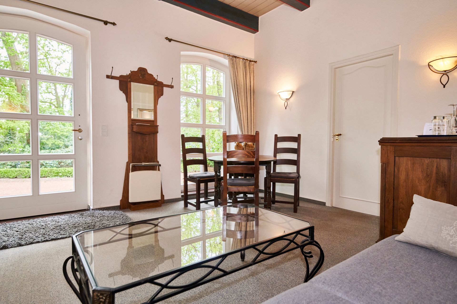 Een woonkamer met een bank, tafel, stoelen en een spiegel.