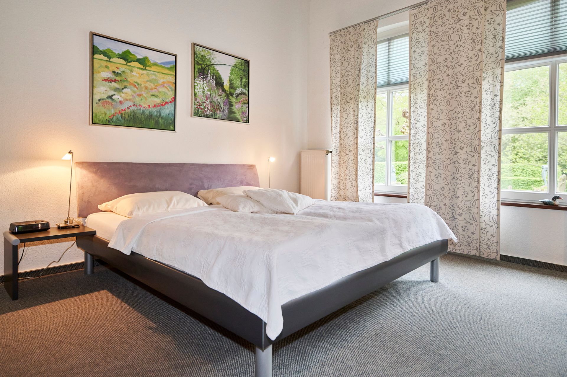 Ein Schlafzimmer mit einem großen Bett und zwei Gemälden an der Wand.