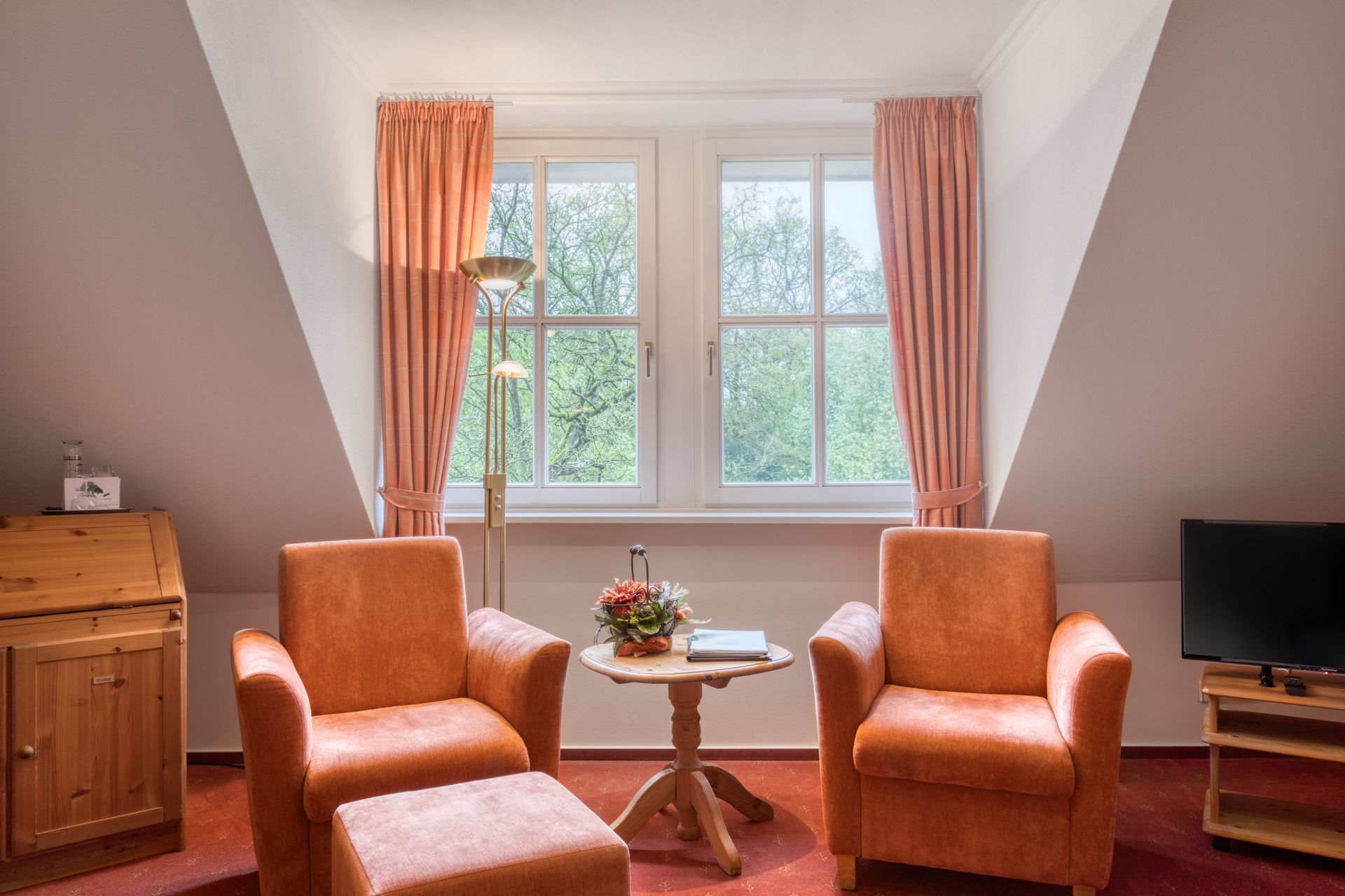 Ein Wohnzimmer mit zwei Stühlen und einem Tisch vor einem Fenster.