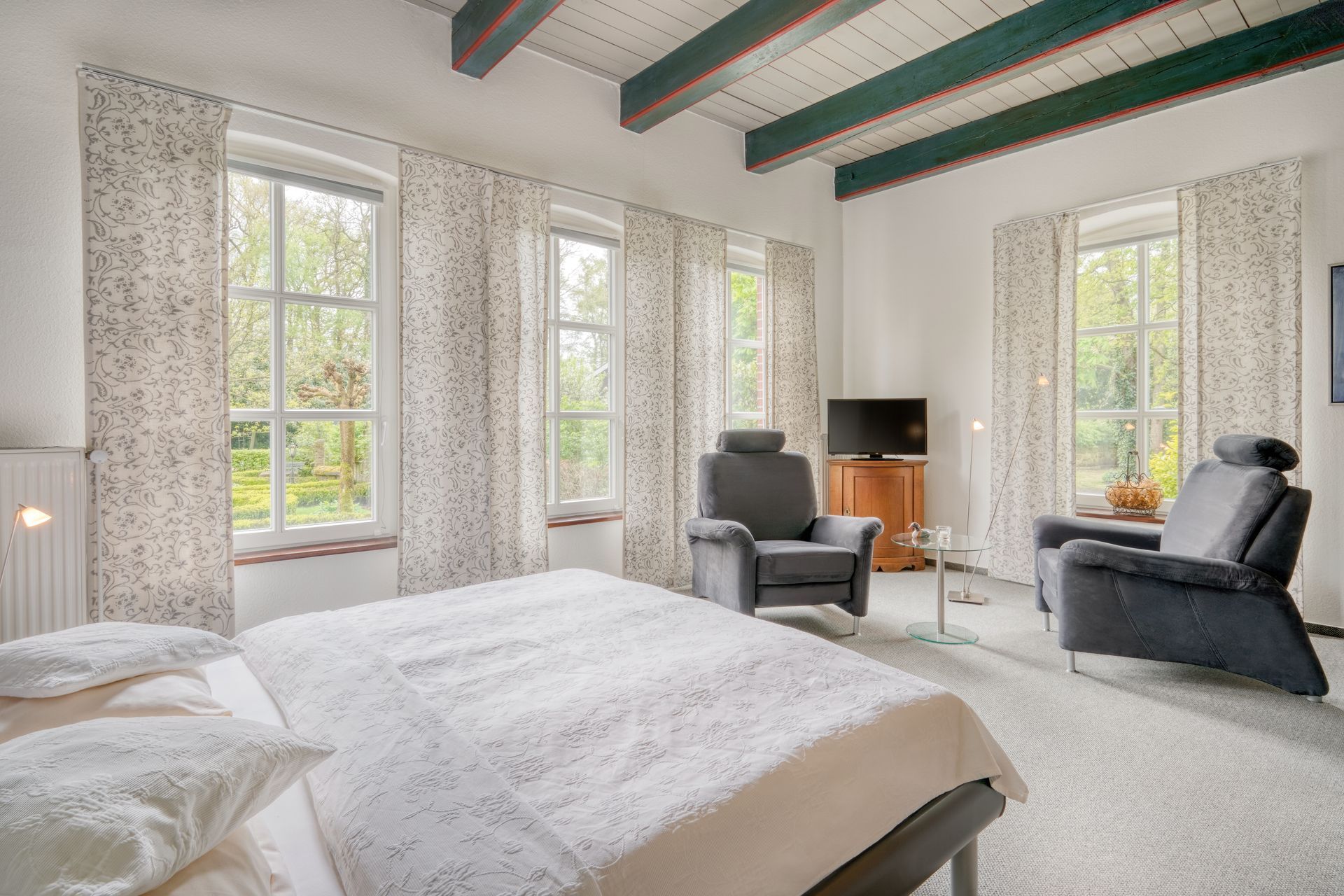 Ein Schlafzimmer mit einem Bett, Stühlen und einem Fernseher.