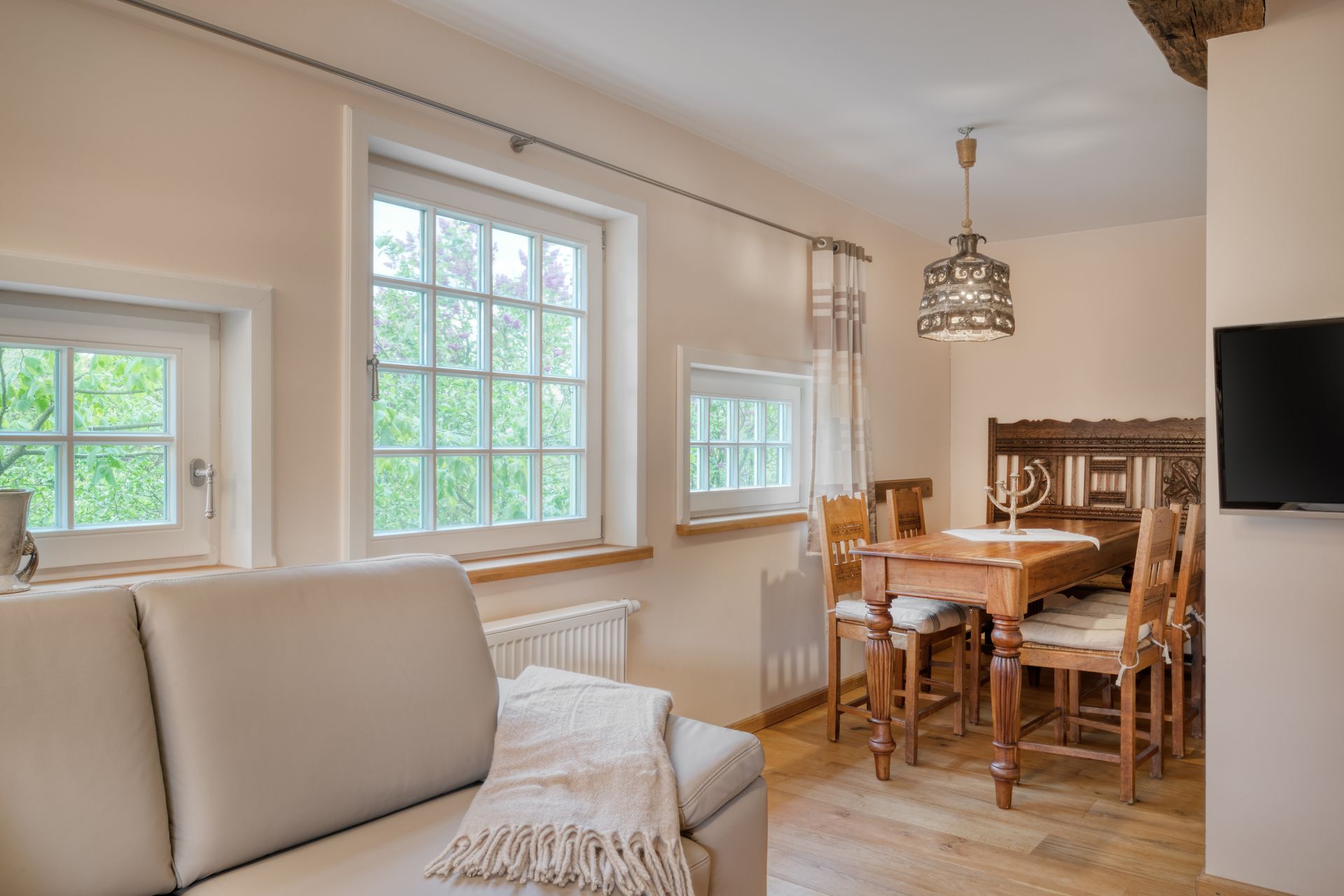 Een woonkamer met een bank, tafel, stoelen en een televisie.