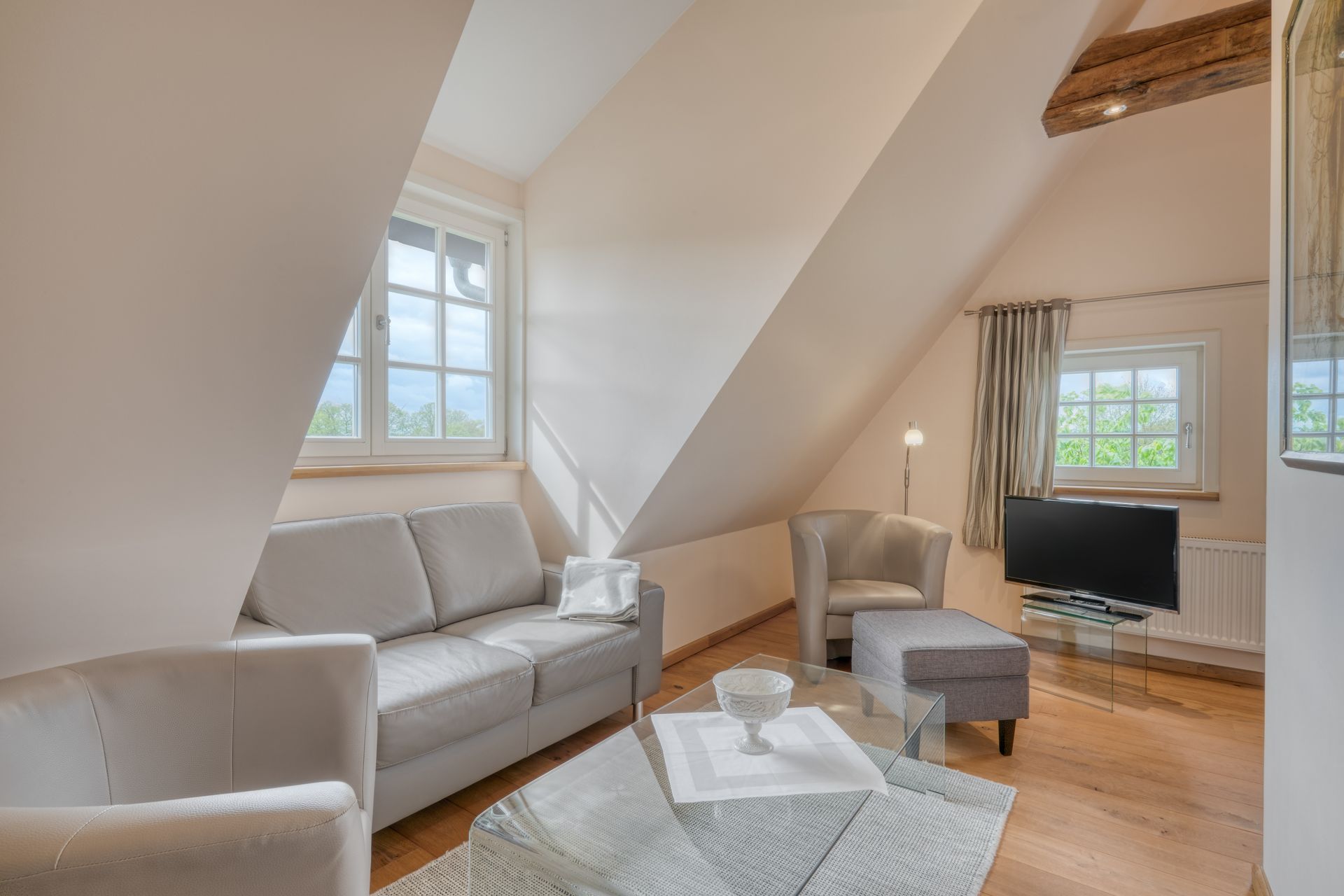 Een woonkamer met een bank, stoelen, salontafel en televisie.