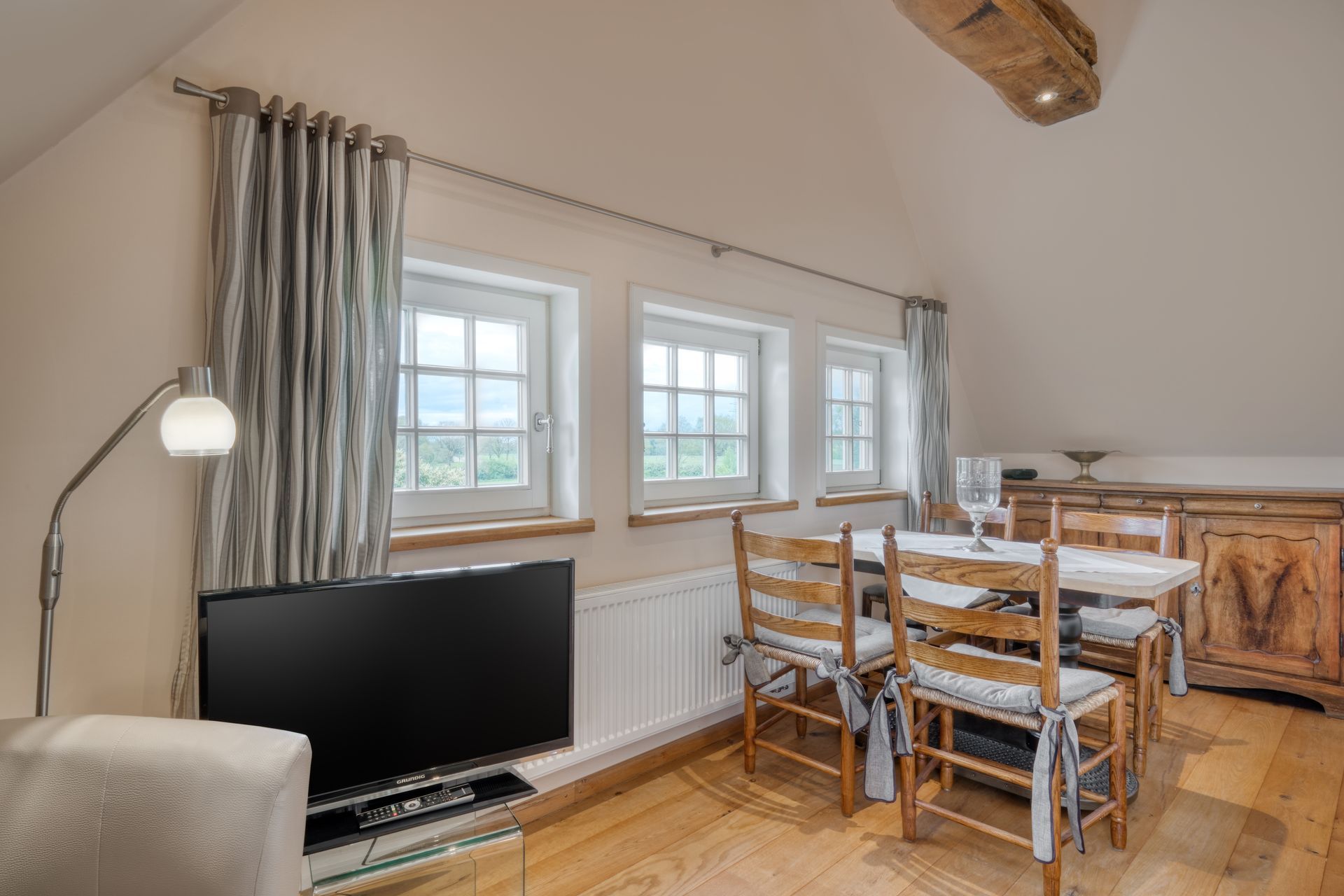 Een woonkamer met een eettafel, stoelen en een flatscreen-tv.