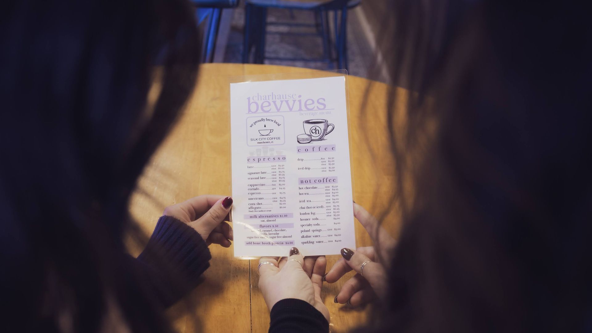 two figures holding a beverage menu