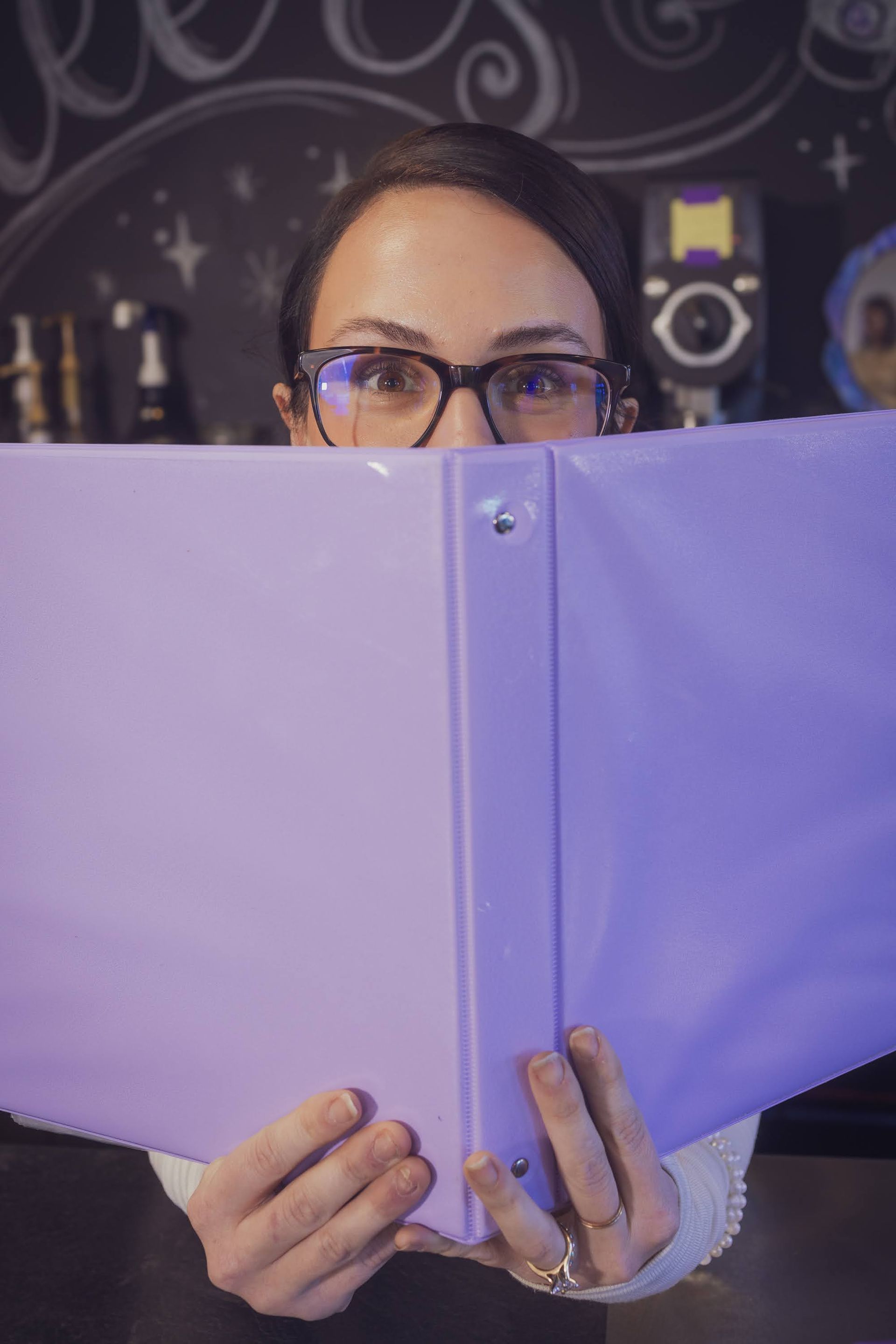 women with glasses looking over a purple binder