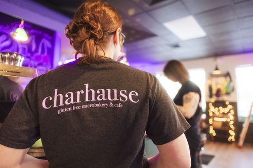 woman's back with charhause written across the back of their shirt with a figure blurred in the distance
