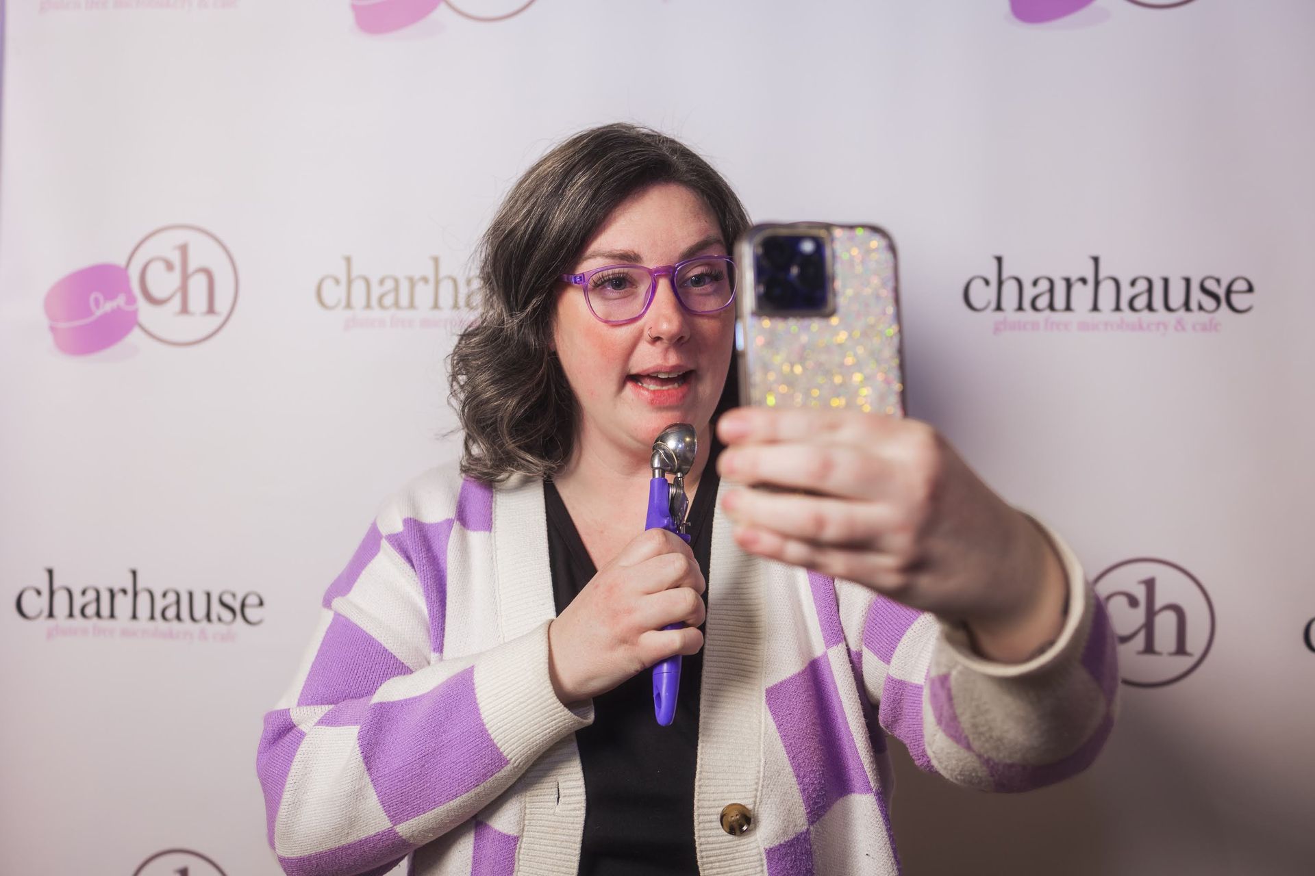 female using an ice cream scoop as a microphone holding up a phone to self record