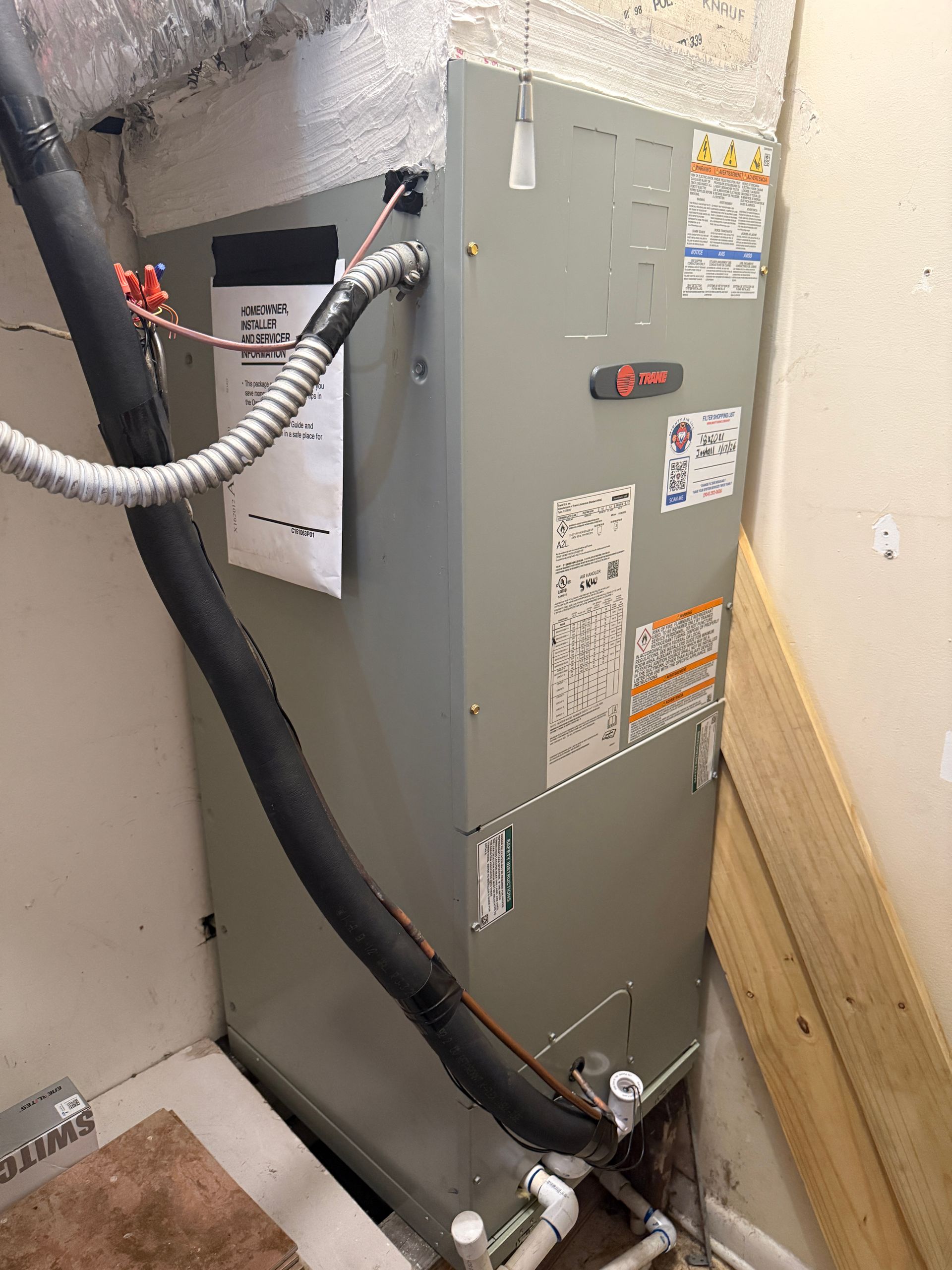 Hand installing a small white device on a wall-mounted air conditioner unit.