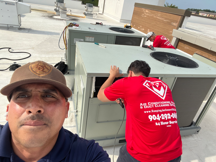 Rooftop cooling units and large HVAC equipment with cables and vents under a cloudy sky