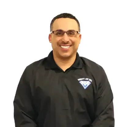 Smiling man in a black polo shirt with a logo, standing against a plain white background