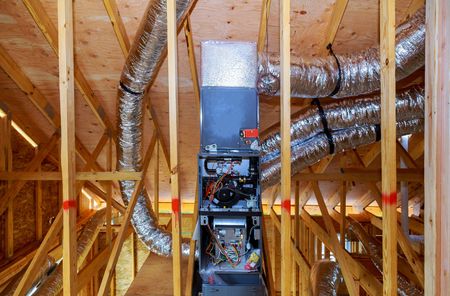 Attic with exposed wooden framing and HVAC ductwork, centered on an open furnace unit.