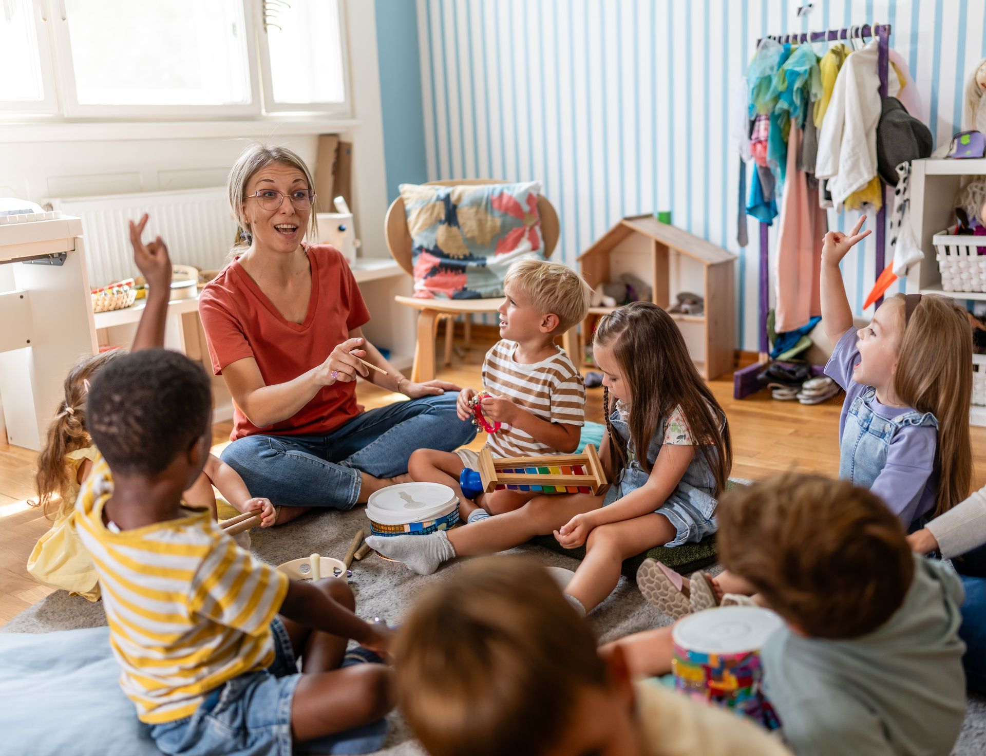 A preschool teacher leading a fun interactive activity with children sitting in a circle.