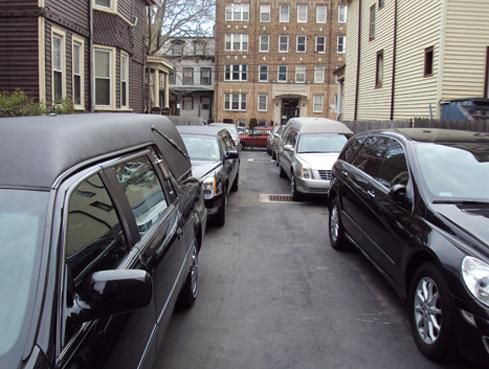 Narrow alley with parked cars between apartment buildings on a wet street