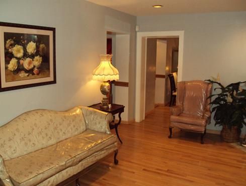 Cozy living room with floral sofa, lamp, chair, and hardwood floors
