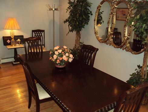 Elegant dining room with dark wood table, chairs, floral centerpiece, lamp, and wall mirrors