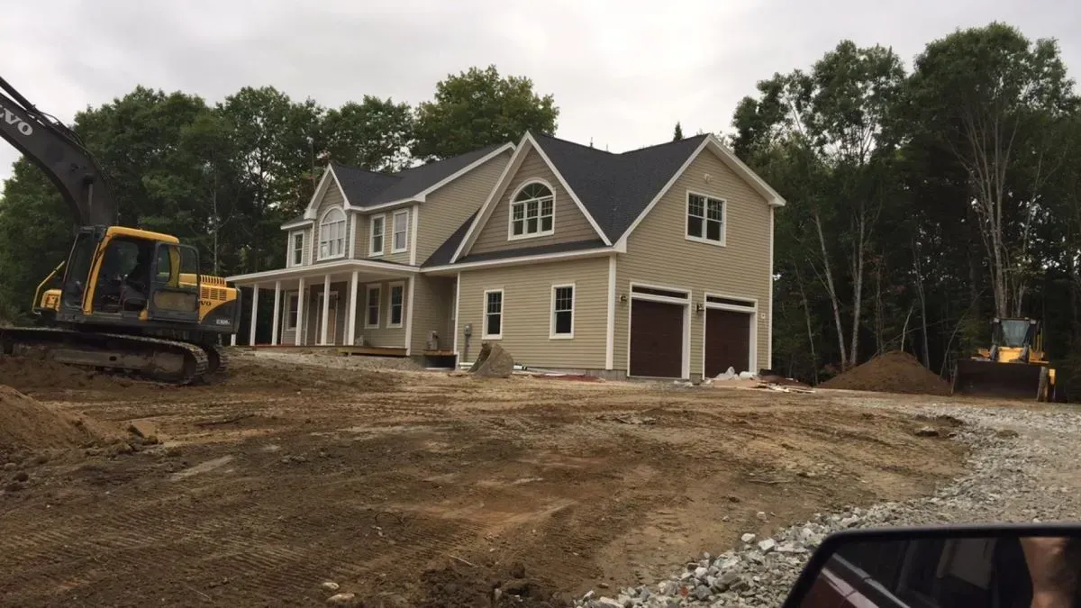 A large house is being built in the middle of a dirt field.