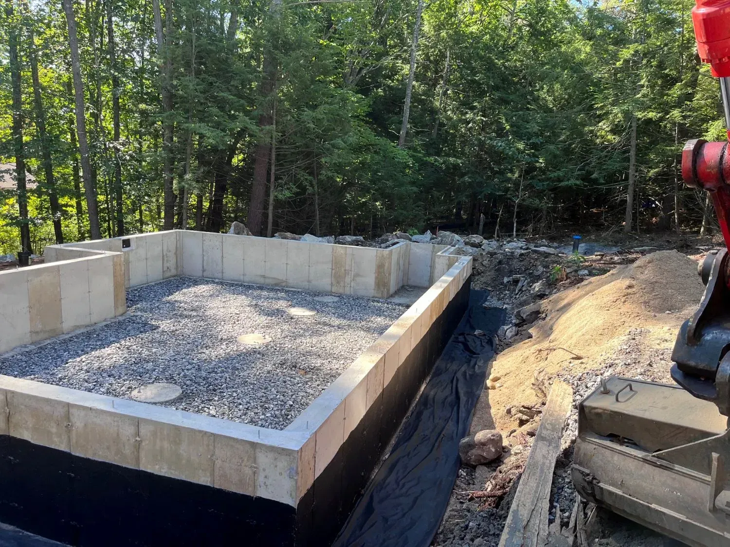 A concrete base for a house is being built in the woods.