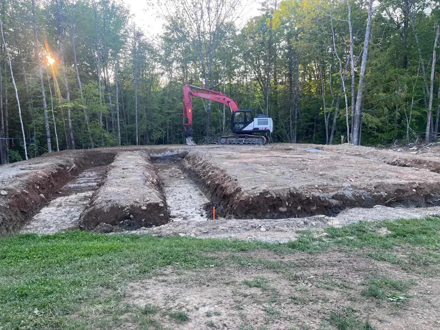 An excavator is digging a hole in the dirt in a field.
