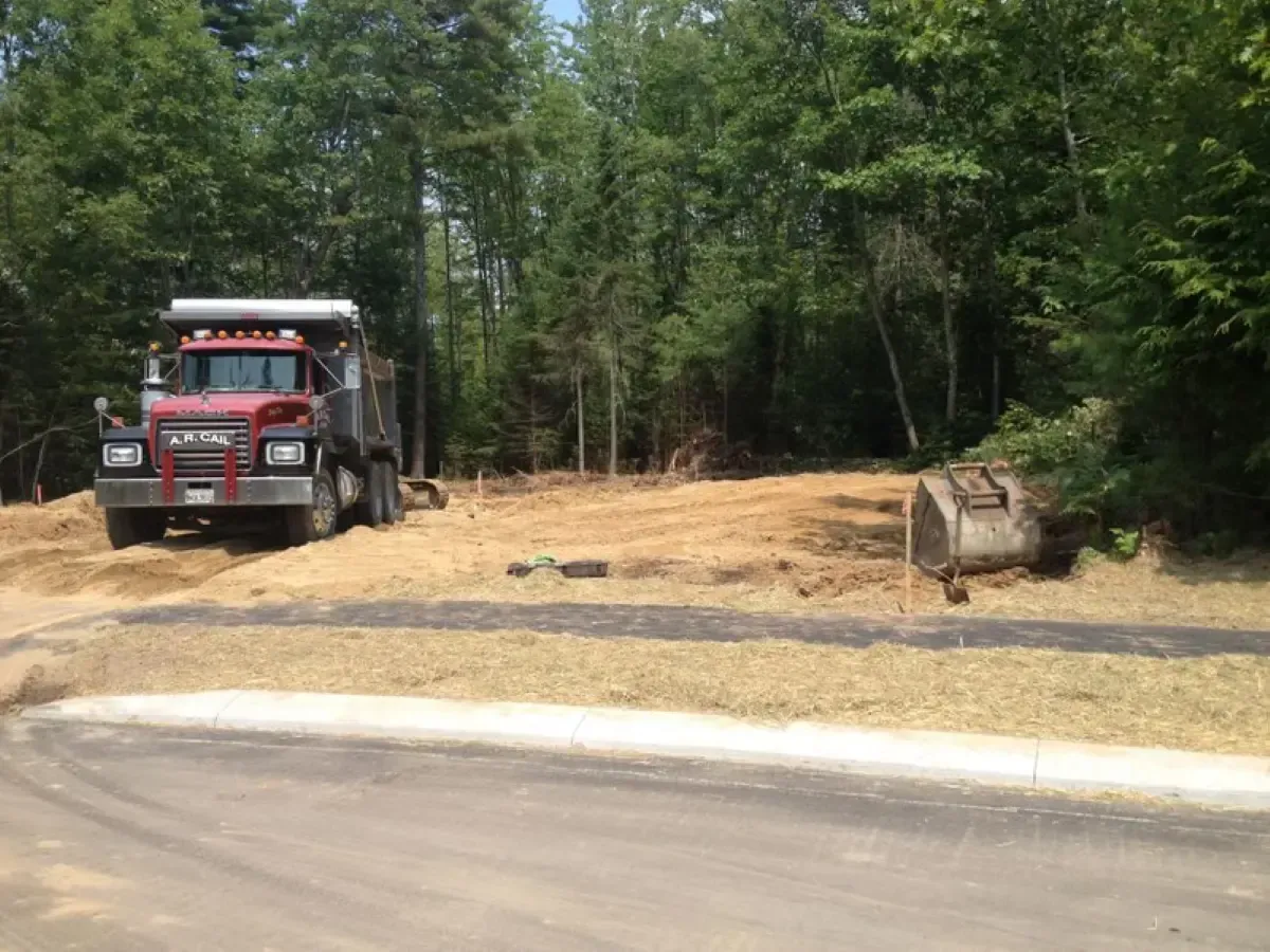 A red dump truck is driving down a dirt road.
