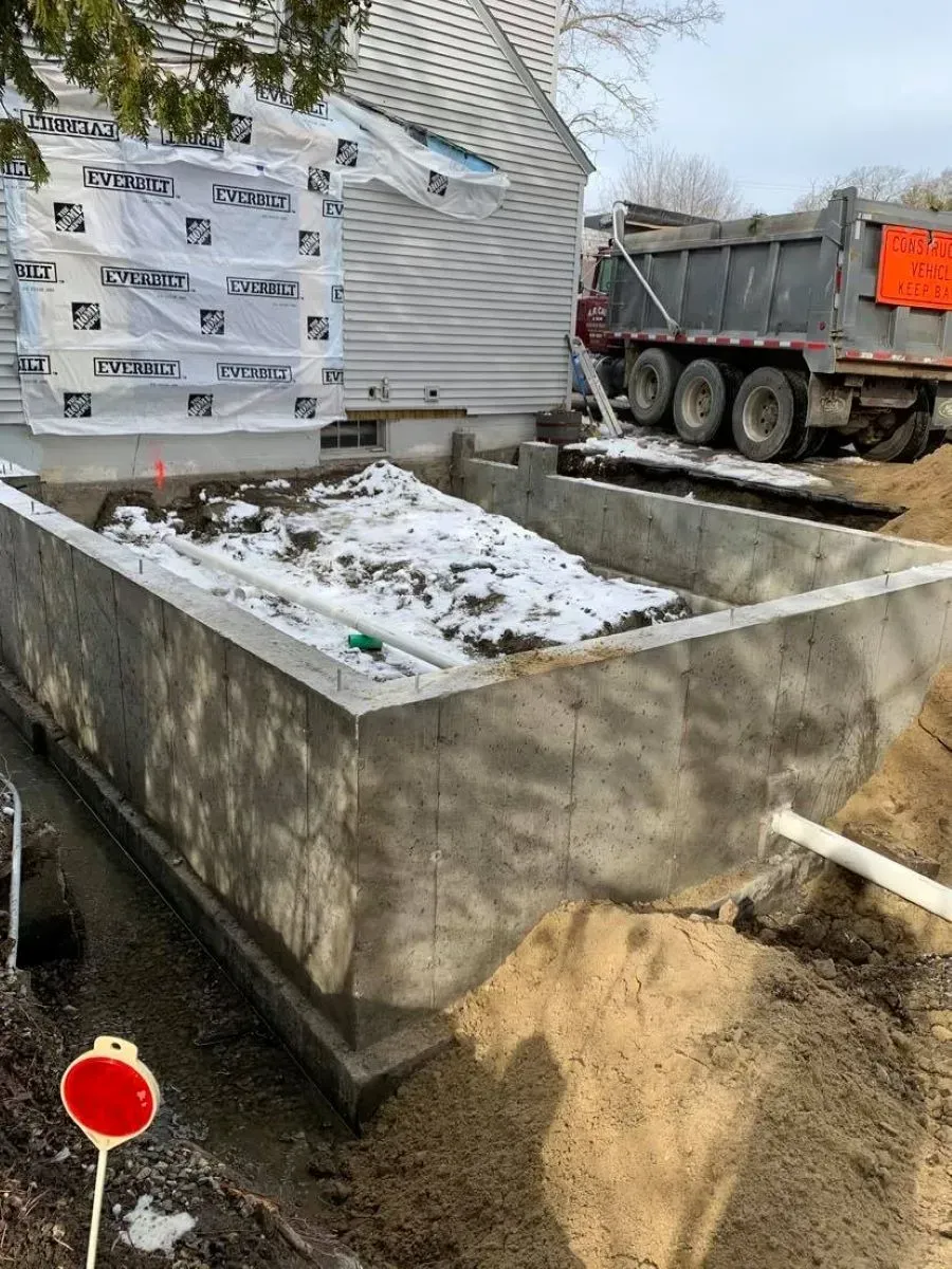 A dumpster is sitting in front of a house under construction.