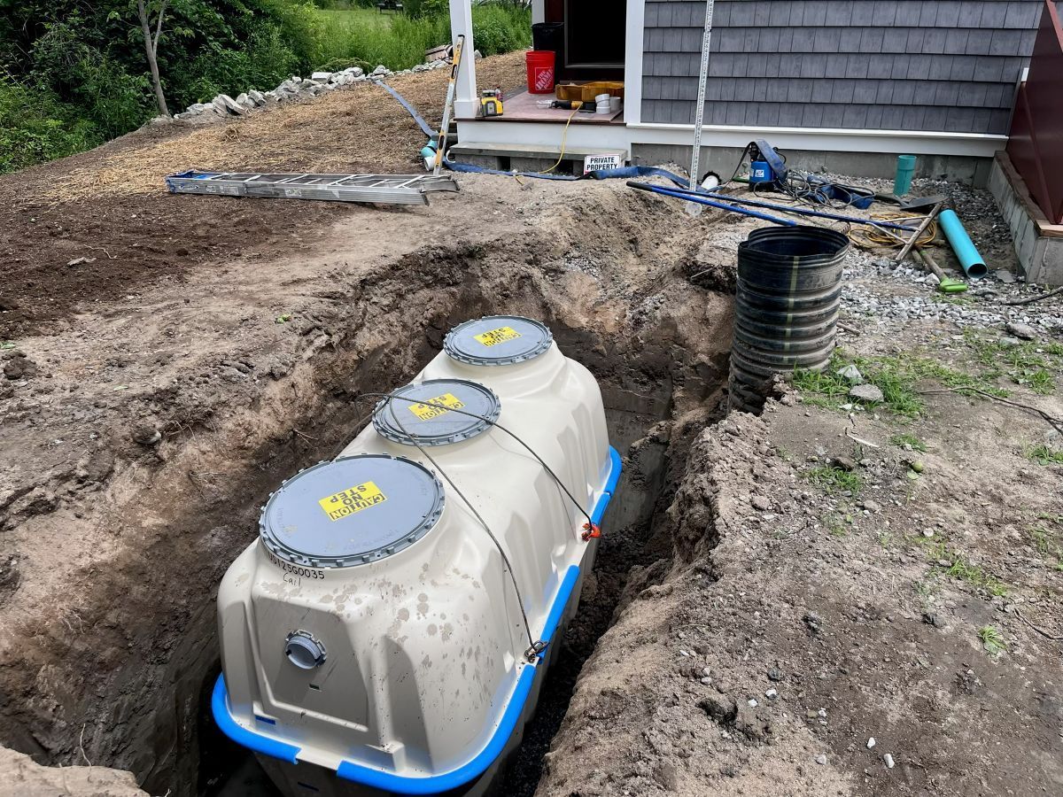 A yellow excavator is digging a hole in the dirt in front of a house.