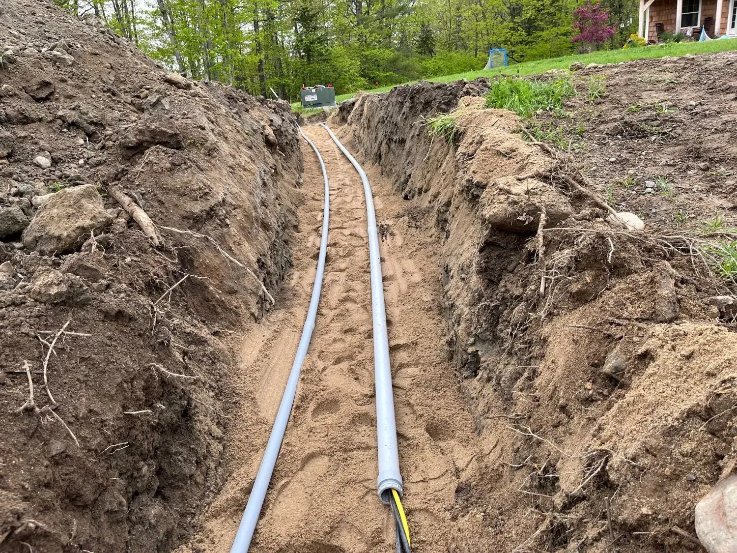 A trench with a bunch of pipes in it.