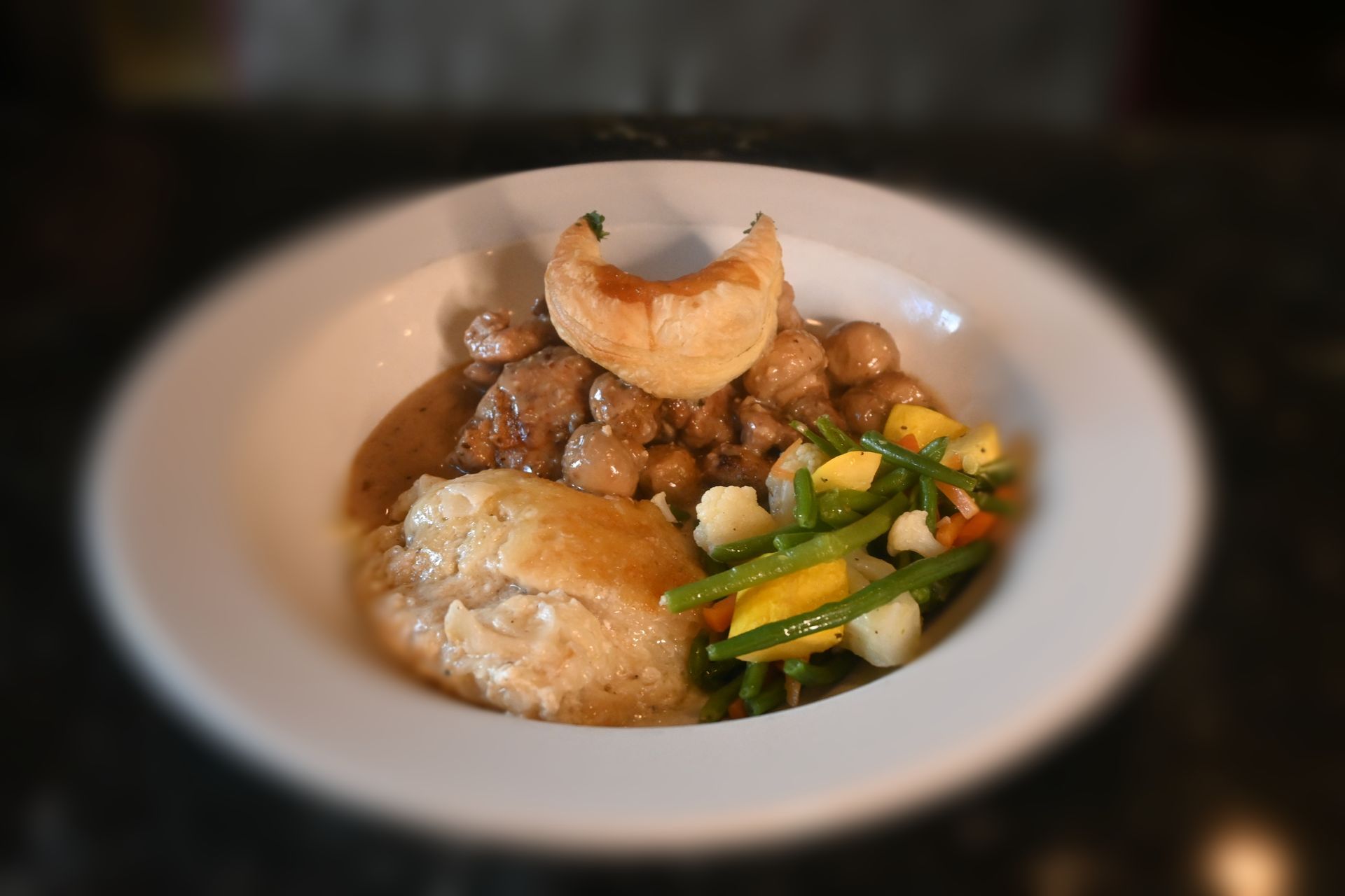 Close-up of a savory entrée plated with sautéed vegetables and tender potatoes, showcasing Chez Pierre Bistro’s French-inspired presentation.