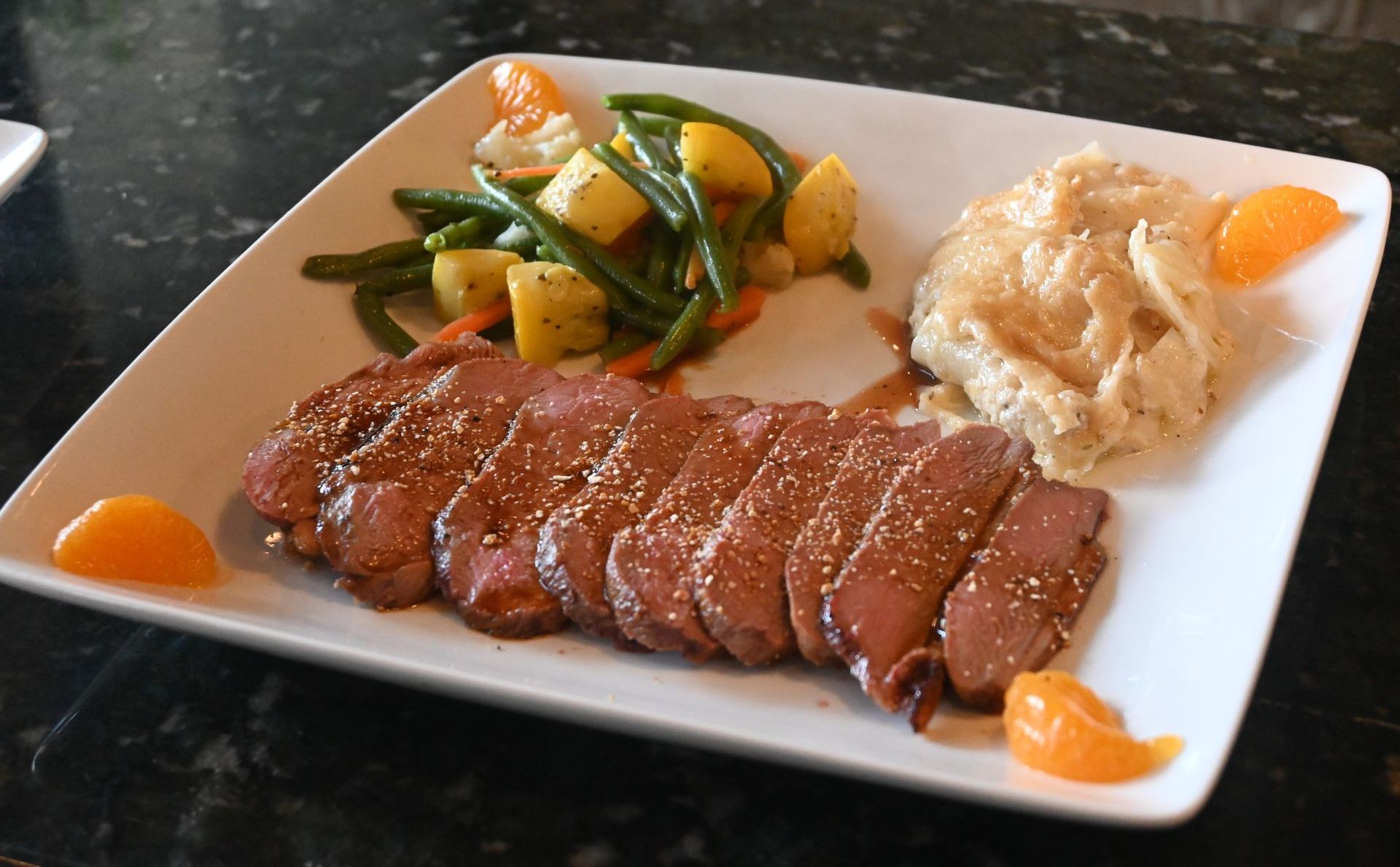 Seared beef entrée plated with seasonal vegetables and a rich sauce, showcasing Chez Pierre’s refined culinary style.